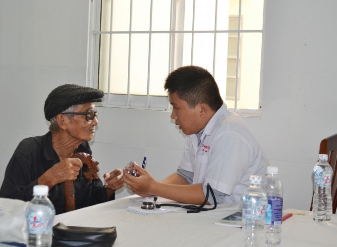 Các bác sĩ tận tình giúp đỡ một cụ già neo đơn vào khám bệnh.