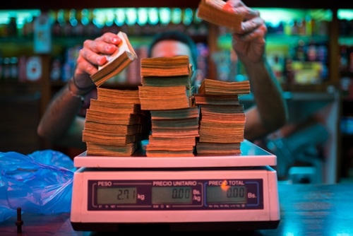 Một chủ tiệm bánh ở Caracas đang cân tiền. Ảnh: Bloomberg