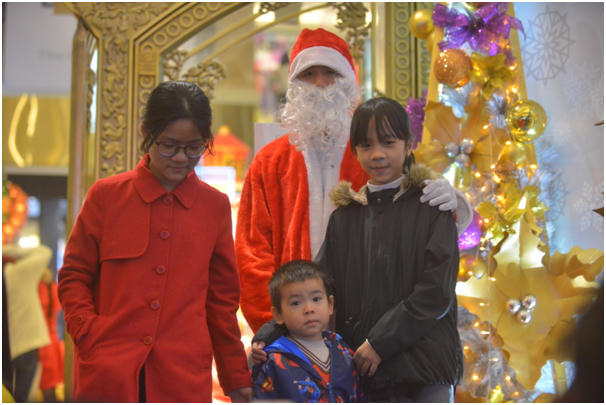 Các em nhỏ thích thú chụp hình với bộ đồ ông già Noel khi đi dạo phố cùng gia đình.
