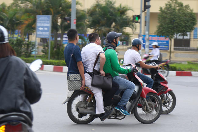 Ở Hà Nội, không khó để bắt gặp hình ảnh tài xế GrabBike kẹp 3, không đội hoặc thiếu mũ bảo hiểm.