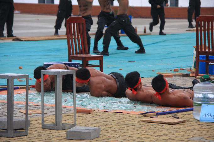 Mình trần lăn trên những miếng thủy tinh vụn trên mặt đất.