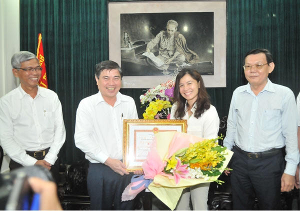 Chủ tịch UBND TP HCM Nguyễn Thành Phong (thứ 2 từ trái qua) trao bằng khen và tặng hoa chúc mùng phóng viên Hàn Ni. (Ảnh: Cao Thăng)