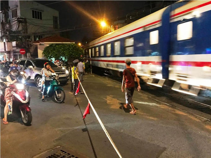 Nhân viên gác tàu phải giăng dây thay thanh chắn vừa bị ô tô hạ gục để điều tiết giao thông khi có tàu lửa chạy qua.