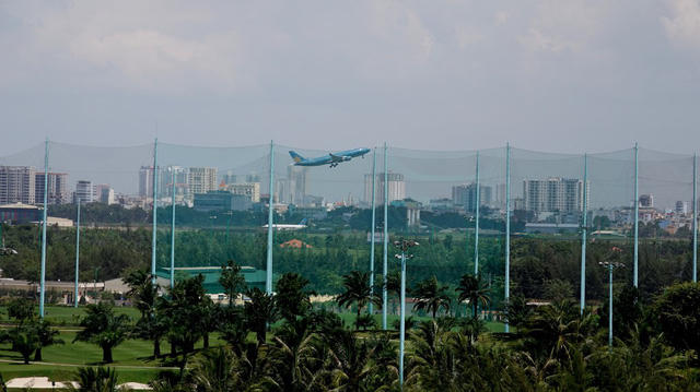 Qua lớp rào lưới chắn bóng, có thể nhìn thấy máy bay đang cất cánh.