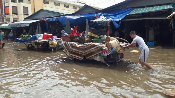 Các tiểu thương bì bõm đẩy hàng ra khỏi khu vực bị ngập để buôn bán.