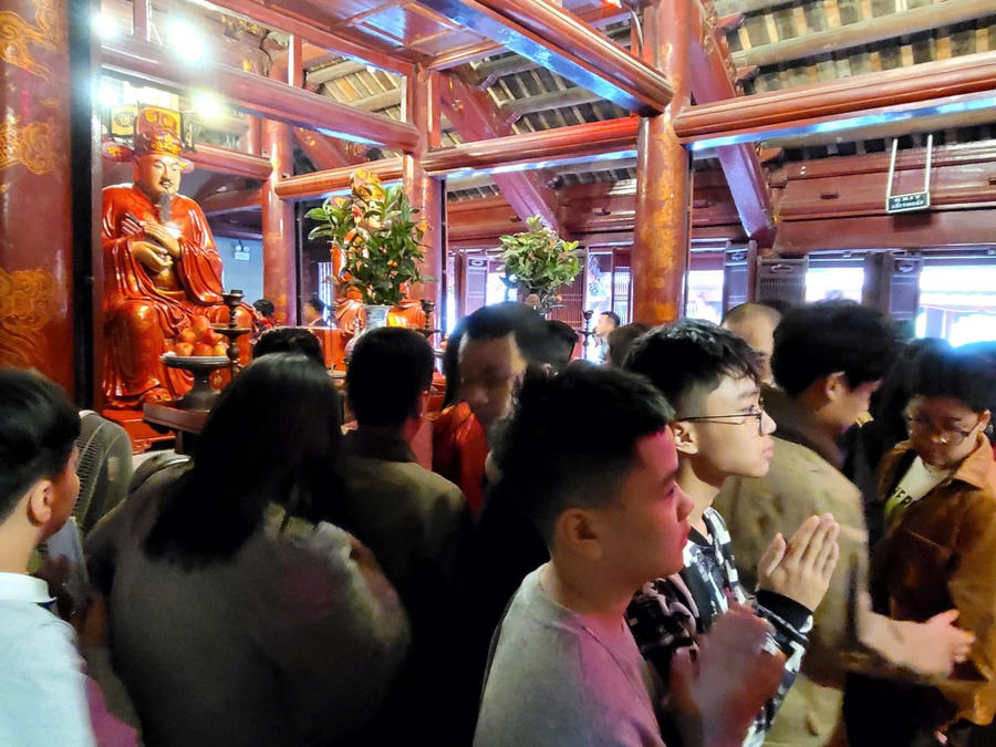 Nhiều bạn trẻ, học sinh sinh viên kính cẩn cầu nguyện, gửi gắm ước vọng về con đường học vấn, công danh trong năm mới. (Ảnh: Phạm Duy)