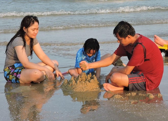 Một gia đình xây lâu đài cát trên bãi biển (Ảnh: N.A).
