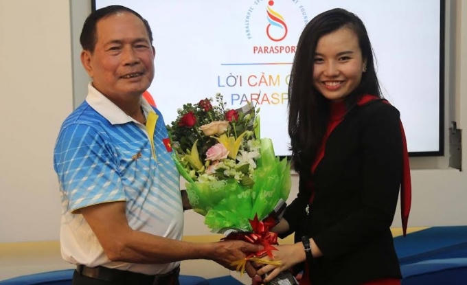 Ông Vũ Thế Phiệt, TTK Hiệp hội Paralympic Việt Nam(trái) nhận hoa chúc mừng từ đại diện nhà tài trợ Parasport.