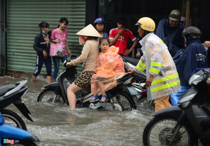 Cảnh sát giao thông cố gắng điều tiết giao thông. Đến 8h cùng ngày nước vẫn chưa rút hết, người dân bì bõm đi lại.