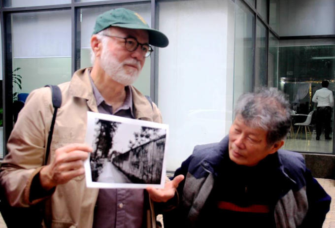 Nhà báo Kennerly với bức ảnh chụp bờ tường trại giam năm xưa. Ảnh: Huỳnh Phan.