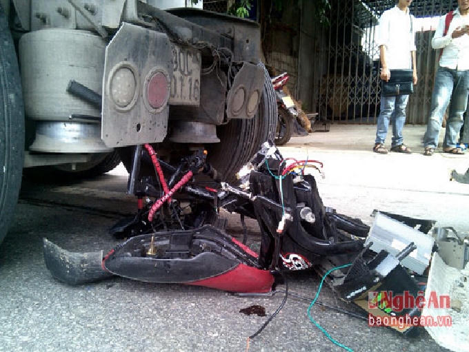 Chiếc xe máy điện bị cuốn dưới gầm xe ô tô, hư hỏng hoàn toàn.