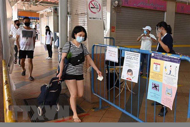 Người dân đeo khẩu trang và thực hiện giãn cách xã hội phòng lây nhiễm dịch COVID-19 tại một chợ ở Singapore. (Ảnh: AFP/TTXVN)