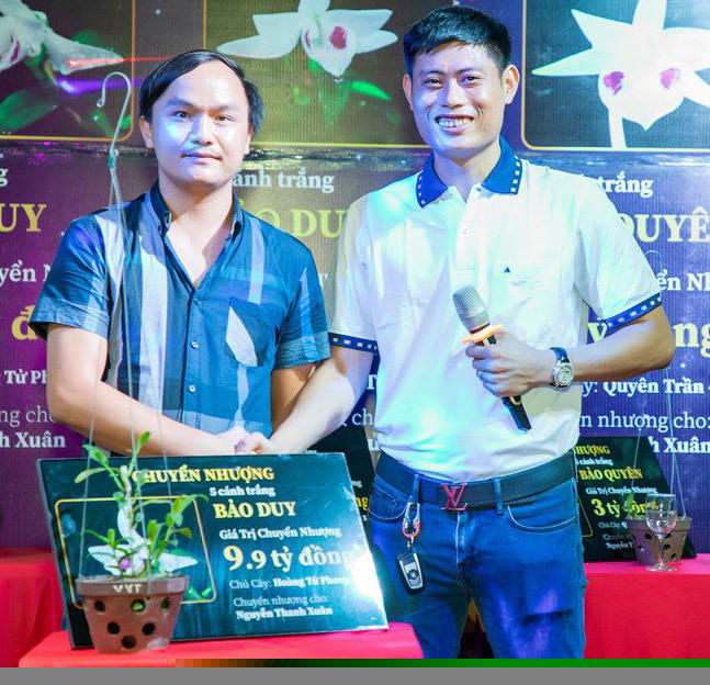 Anh Nguyễn Thanh Xuân (bên phải) cạnh chậu lan Bảo Duy 5 cánh trắng trị giá 9,9 tỷ đồng được chuyển nhượng hôm 10/6.