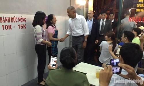Ông Obama bước vào quán bún chả, tươi cười bắt tay nữ chủ quán bún chả. (Ảnh: Tiền phong)
