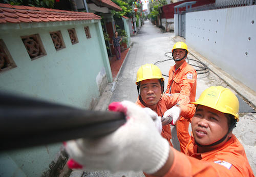 Công nhân ngành điện kéo cáp điện đến nhà khách hàng. Ảnh: Ngọc Thành