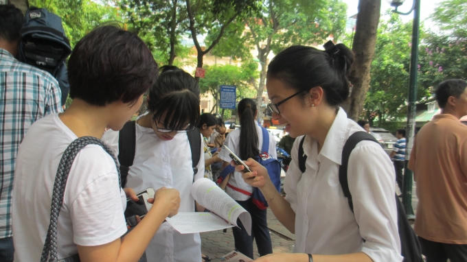 Hai bạn thí sinh cùng mẹ xem lại đề thi môn Ngữ Văn. (ảnh: Thu Hường)