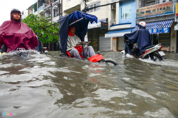 Trong khi đó, một người đàn ông ngồi xe đạp 3 bánh cố vượt qua đoạn ngập trên đường Phan Anh (quận 6) để bán vé số.