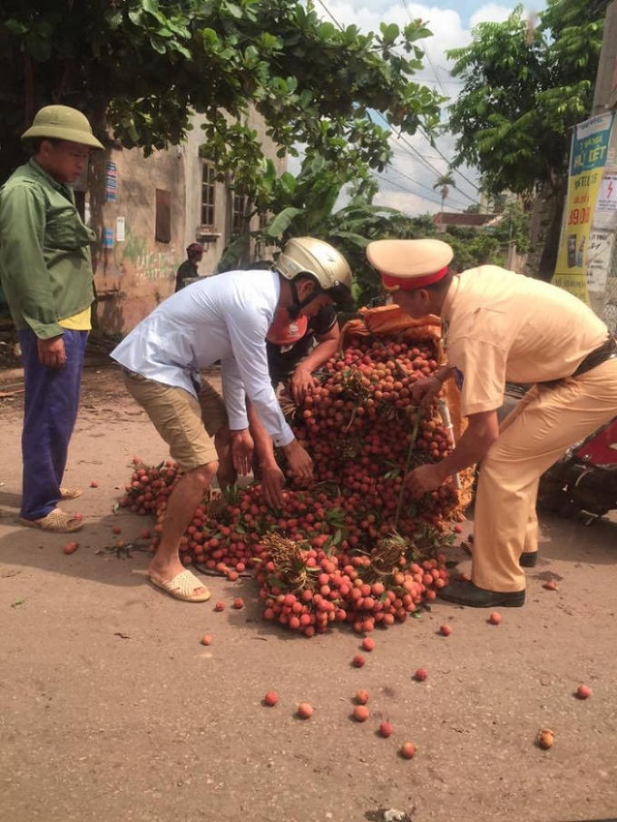 Cảnh sát giao thông giúp người dân nâng xe vải bị đổ.