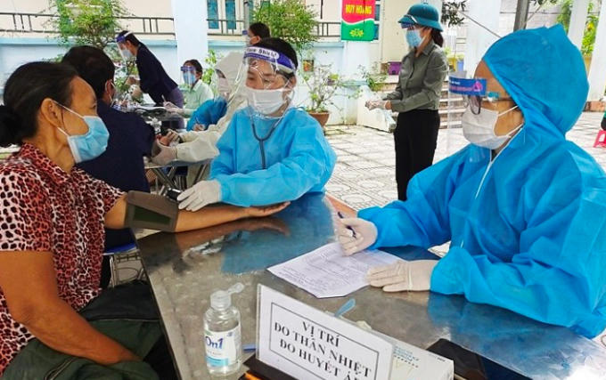 Người dân đo thân nhiệt trước khi tiêm phòng vaccin Covid 19.