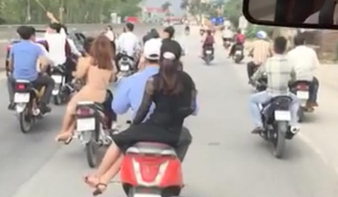 H&igrave;nh ảnh đo&agrave;n người điều khiển h&agrave;ng chục xe m&aacute;y kh&ocirc;ng đội mũ bảo hiểm, d&agrave;n h&agrave;ng, lạng l&aacute;ch tr&ecirc;n quốc lộ (ảnh cắt từ clip).
