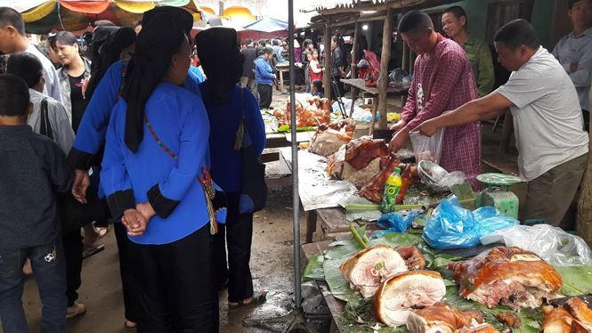 Người Tày- Nùng vận quần áo dân tộc đi mua thịt lợn quay về đãi khách. Ảnh: Duy Chiến.