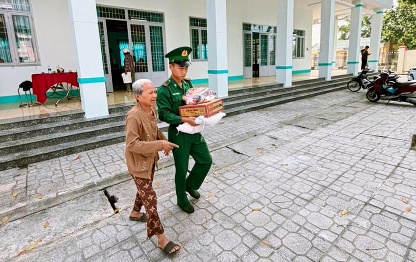 Cán bộ, chiến sĩ Đồn Biên phòng Vàm Trảng Trâu hỗ trợ bà con nhận quà