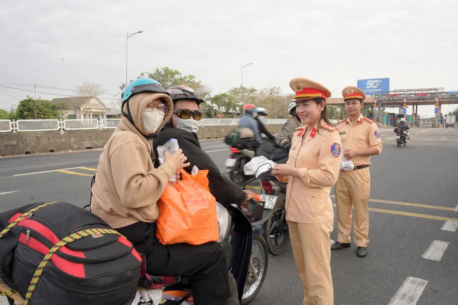 Cán bộ Cảnh sát giao thông Cà Mau phát nước, bánh đến tận tay người dân về quê đón Tết tại tuyến Quốc lộ 1.