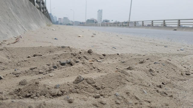 Cát, đá tụ lại thành lớp dày trên hai mép cầu vượt An Khánh.