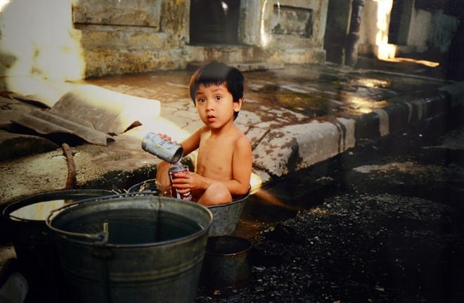 Em Phong nghịch nước trong khi tắm tr&ecirc;n phố Ph&ugrave;ng Khắc Khoan m&ugrave;a h&egrave; năm 1983.