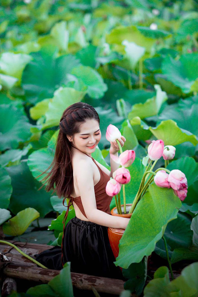 Chọn cho mình trang phục áo dài trắng và áo yếm, cô gái sinh năm 1999, nổi bật giữa hồ sen nhờ ngoại hình được nhiều người ví như búp bê.