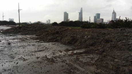 Bùn đất thải được đổ tràn ra lòng đường lấp cả miệng cống thoát nước - Ảnh Quang Huy