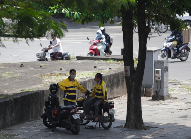 Những người làm xe ôm công nghệ tìm bóng mát nghỉ ngơi đợi khách.