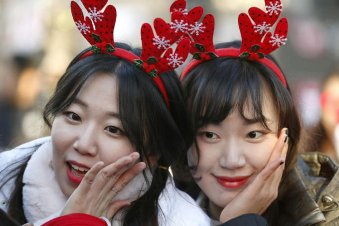 Các tình nguyện viên Hàn Quốc chụp ảnh tự sướng trong sự kiện từ thiện đêm Giáng sinh ở thủ đô Seoul, Hàn Quốc, ngày 24/12. Ảnh: EPA.