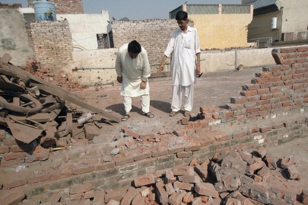 Một bức tường bị đổ sau cuộc đấu pháo giữa Pakistan và Ấn Độ đêm 24/10. (Ảnh: AFP)