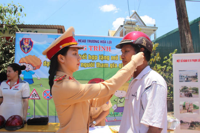 CSGT Đắk Lắk hướng dẫn người dân đội mũ bảo hiểm và cài quai đúng cách khi tham gia giao thông. (Ảnh: Đình Thảo)