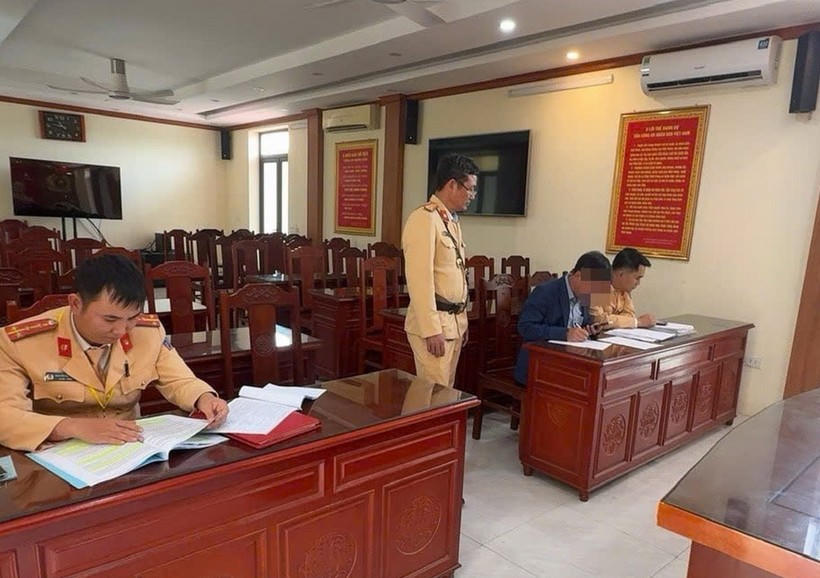 Lực lượng chức năng làm việc với người vi phạm. (Ảnh: VietnamPlus)