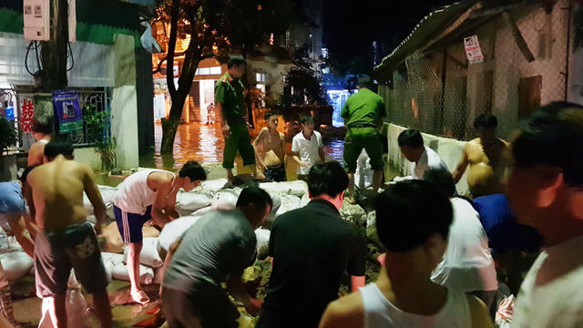 Người dân và cơ quan chức năng tích cực đắp bao cát, đất để ngăn chặn dòng nước.