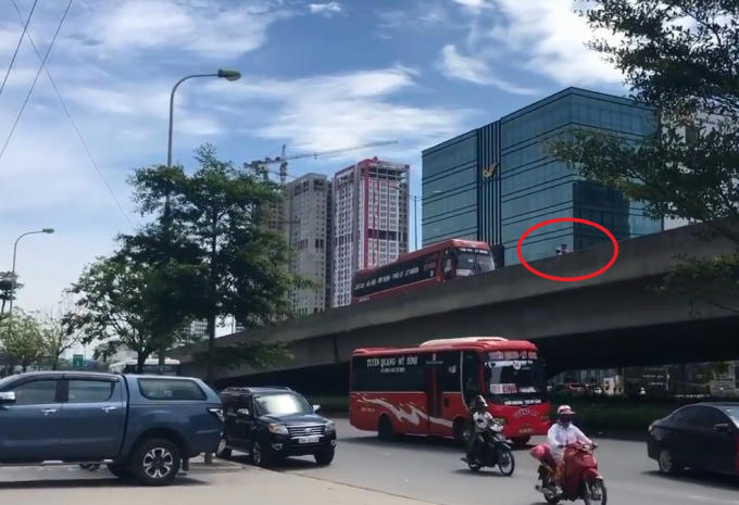 Hai người đàn ông đi xe máy (vòng tròn đỏ) ép chiếc xe khách đi lùi trền đường vành đai 3.