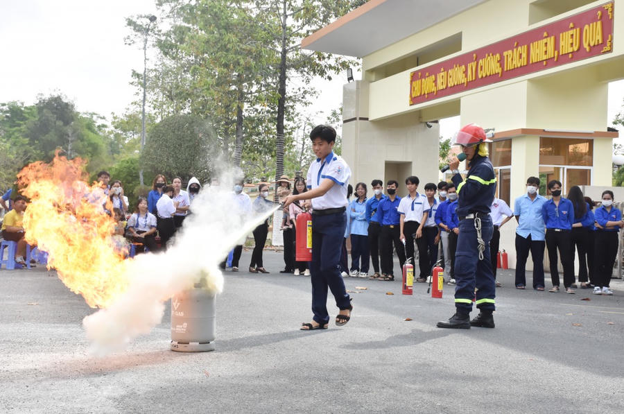 Cán bộ, chiến sĩ Công an tỉnh hướng dẫn học sinh sử dụng bình chữa cháy xách tay để dập lửa.