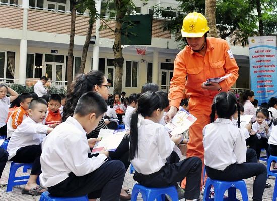 Công nhân EVN Hà Nội phát tờ rơi cách thức sử dụng điện an toàn tiết kiệm tới học sinh trường tiểu học Nghĩa Tân.