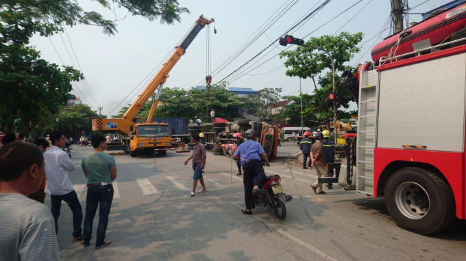 Lực lượng chức năng tiến hành cẩu xe container và cứu các nạn nhân trong xe ô tô con.