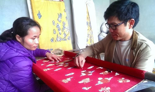 Nghệ nhân nhân dân Vũ Văn Giỏi đang hướng dẫn thợ thêu một số kỹ thuật thêu truyền thống.