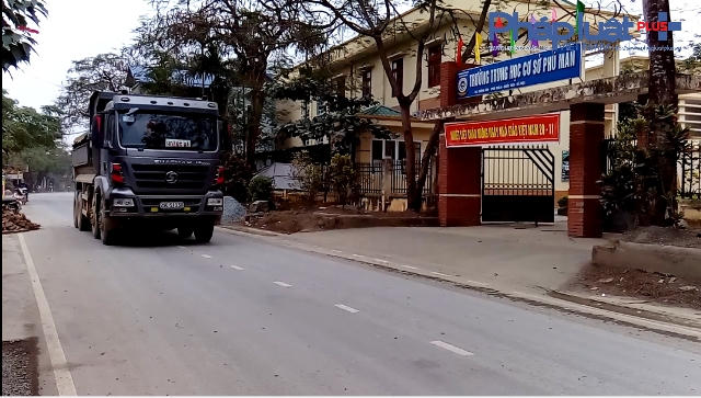 Xe tải chạy qua trường trung học cơ sở.
