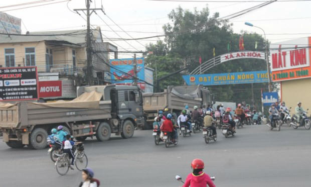 Xe ben chạy thành từng tốp trên đường nông thôn mới đang xuống cấp.