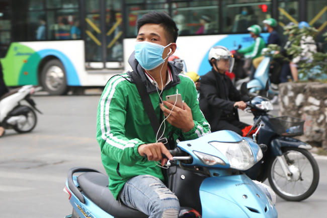 Một tài xế đầu trần, đeo tai nghe, lái xe bằng một tay còn một tay cầm điện thoại rất nguy hiểm trên đường.