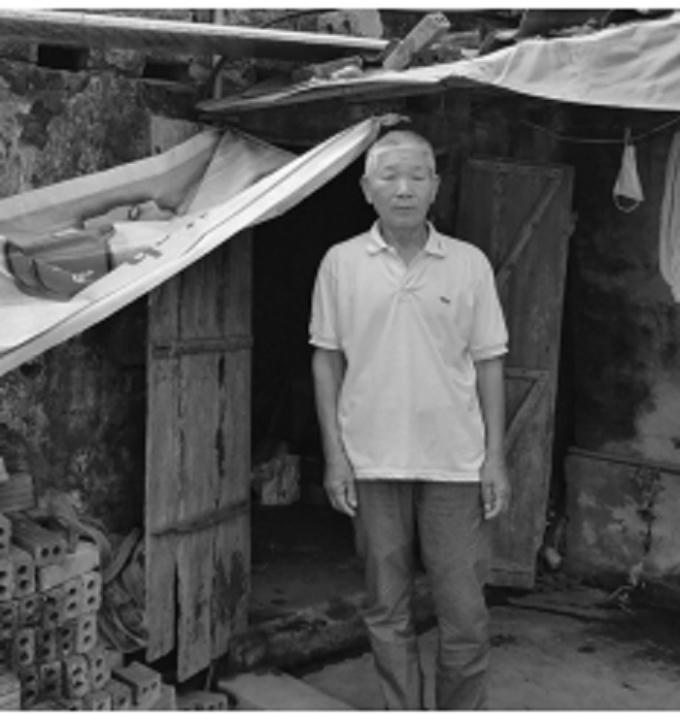 Ông Trắc bên căn bếp dột nát của gia đình.