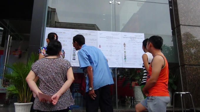 Cử tri phường 12, quận 4 chăm chú nghiên cứu tiểu sử ứng viên trước khi quyết định bầu.