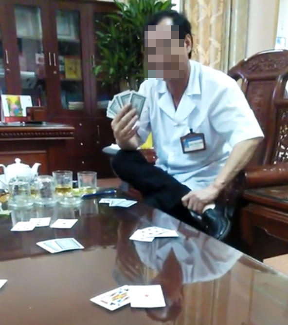 Hình ảnh ông Đặng Trung Bình, Giám đốc BVĐK huyện Gia Viễn mặc áo blouse trắng ngồi đánh bài ăn tiền bị tung lên mạng xã hội.