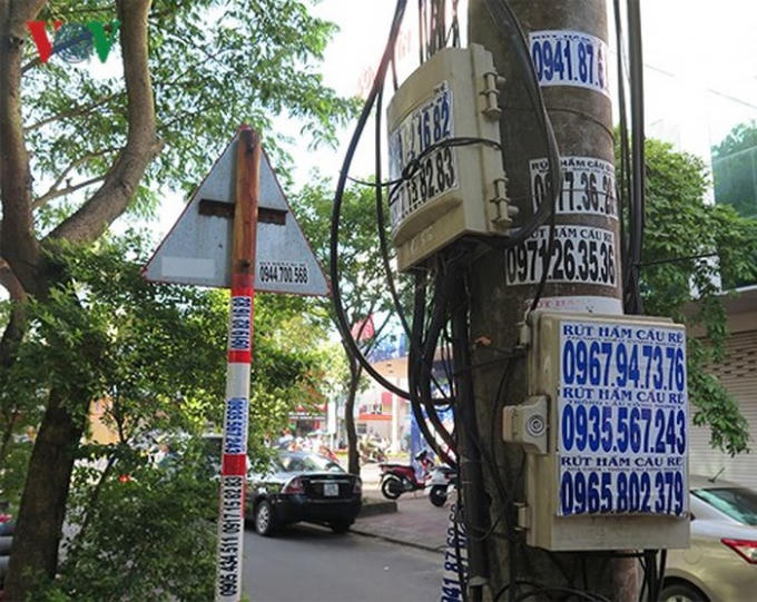 Hàng chục mẩu quảng cáo rao vặt dán dày đặt trên cột điện.