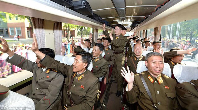 Các nhà khoa học hạt nhân Triều Tiên vẫy tay chào người dân đứng hai bên đường khi họ được mời tới Bình Nhưỡng để vinh danh sau vụ phóng thành công tên lửa đạn đạo mới vào tháng 5/2017 (Ảnh: AFP)